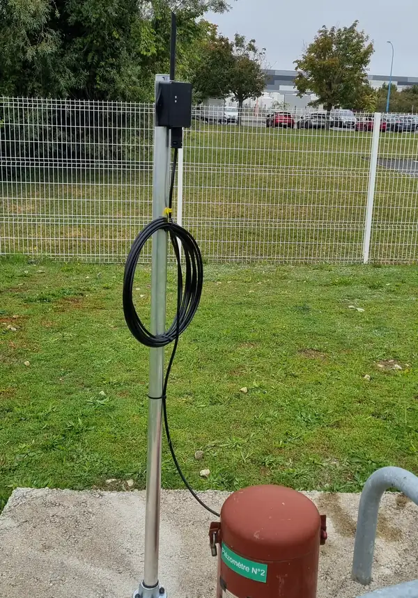 Capteur de niveau Dragino PS-CS-I solaire fixé sur un mât, mesurant la hauteur d'eau d'un puits