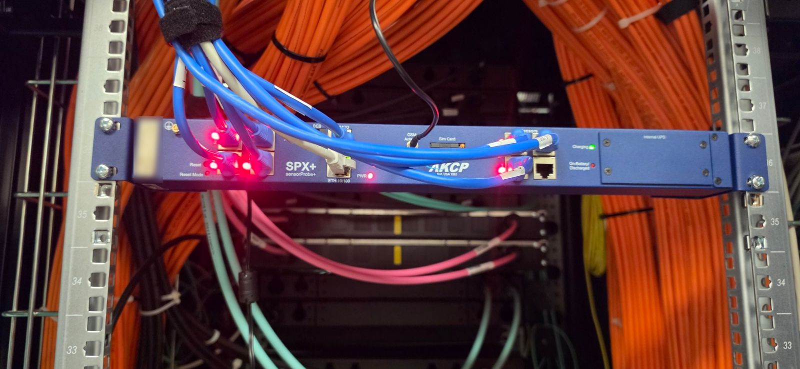 Centrale AKCP SPX+ montée en baie 1U, avec antenne GSM, ports capteurs câblés et module UPS interne